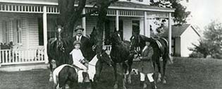 Cy Cummings family photo with their horses and pony in front of Pleasant Grove